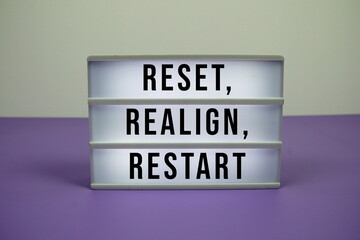 Reset, Realign, Restart text on LED lightbox on purple background