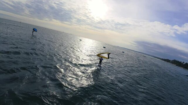 Aerial View of Winging, Wing Foiling, Wind Surfing in Vietnam waters on a beautiful summers day. Aerial pan of action packed water sports.