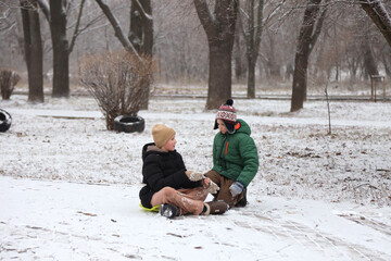 Children are walking, hiking,, sledding and playing in a snowy park. Winter fun and outdoor activities with kids