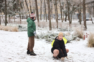 Children are walking, hiking,, sledding and playing in a snowy park. Winter fun and outdoor activities with kids