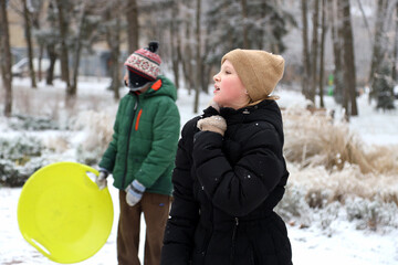 Children are walking, hiking,, sledding and playing in a snowy park. Winter fun and outdoor activities with kids