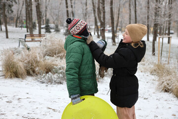 Children are walking, hiking,, sledding and playing in a snowy park. Winter fun and outdoor activities with kids