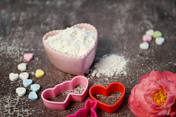 Heart-shaped cookie cutters, flour in a pink bowl, pastel candie