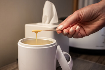 Hand holding stick with melted wax over a wax warmer