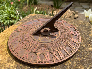 Old Sundial Bronze on Rustic Concrete in Bright Flower Garden