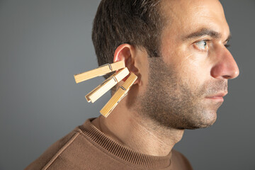 Clothespins on a caucasian male ear.