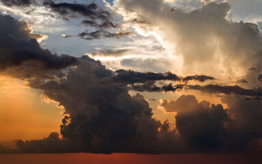 Bright sunset with setting sun behind vivid orange and yellow clouds