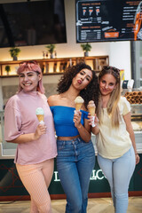 Three young women holding ice cream cones and having fun