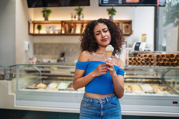 Young woman disliking ice cream flavor in ice cream shop