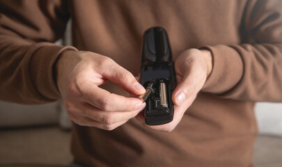 Man installs a new battery in the remote control of a TV.