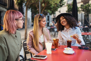 Three young women talking and having drinks at outdoor cafe