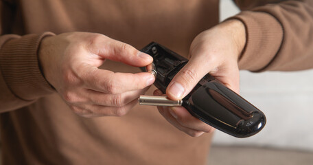 Man installs a new battery in the remote control of a TV.