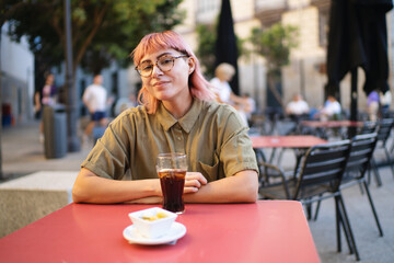 Young woman enjoying a refreshing drink and snack at outdoor cafe