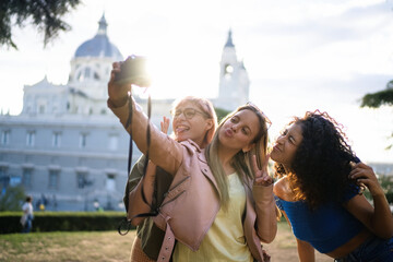 Three playful tourists taking a selfie in a park