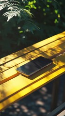 Smartphone Resting on Yellow Bench in Sunny Park Setting