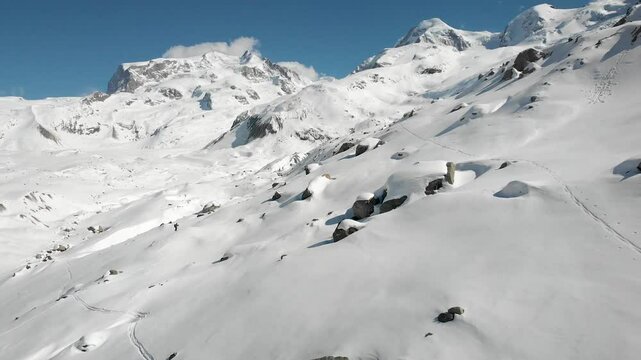 Aerial view of a skier on a ski tour adventure next to snow covered Gorner glacier in Zermatt, Switzerland on a sunny winter day with a view of the tallest peaks of the Swiss Alps including Monte Rosa