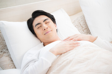 ベッドで寝る男性　安眠のイメージ