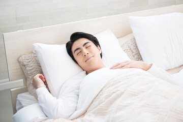 ベッドで寝る男性　安眠のイメージ