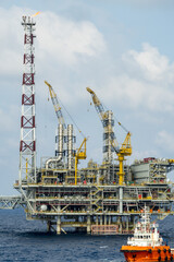 An offshore anchor handling tug boat manouevring near a oil production platform at offshore oil field