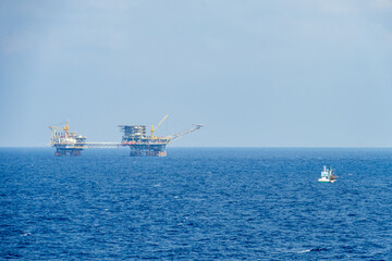 A fisherman boat navigating near an oil production platform at offshore oilfield