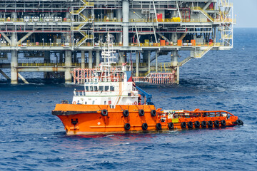 An offshore anchor handling tug boat sailing near a oil production platform at offshore oil field