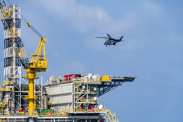 A helicopter about to land on an oil production platform for transferring of offshore crew at oil field