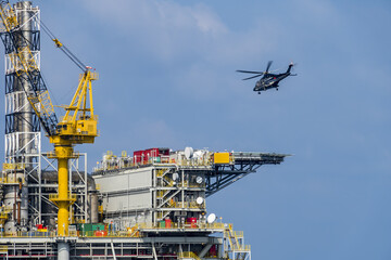 A helicopter about to land on an oil production platform for transferring of offshore crew at oil field