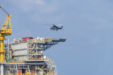 A helicopter about to land on an oil production platform for transferring of offshore crew at oil field.