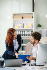 Two business workers talking on the smartphone and using laptop at office.