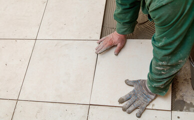 A man is laying tiles on a floor