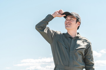 青空の下にいるつなぎ姿の作業員・整備士の男性
