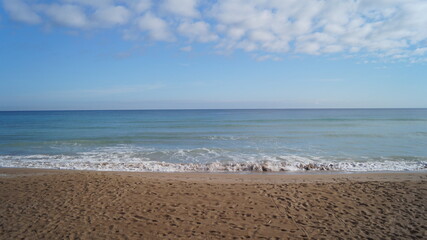 Sandy beach on a calm day with a few clouds