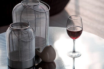A glass of red alcoholic drink or wine on a glass table on the veranda. The concept of alcoholism,...