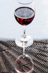 A glass of red alcoholic drink or wine on a glass table on the veranda. The concept of alcoholism, a party, or a holiday.