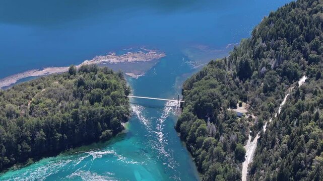 A stunning high aerial view of the suspension bridge spanning the River Arrayanes in Parque Nacional Los Alerces, Argentina, showcasing the lush landscapes and natural beauty of the region.