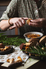 woman preparing wild edible forest mushrooms (chanterelles) in rustic cottage kichen