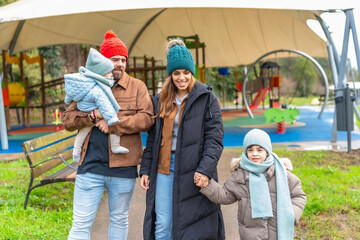 Happy family walking in playground wearing winter clothes