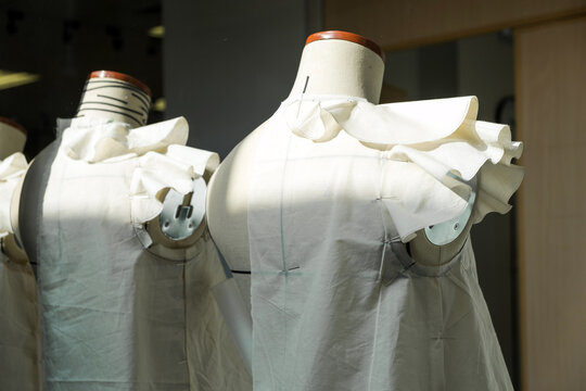 Two dress forms adorned with elegant white fabric display unique designs, showcasing the artistry and craftsmanship of fashion creation. Fashion design school business concept.