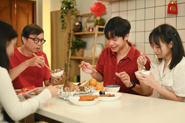 Family gathering around the table for a Chinese New Year meal, sharing food and laughter