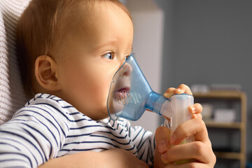 A toddler sits comfortably while a caregiver administers nebulizer treatment. The cozy interior...