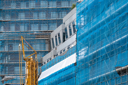 A construction site encapsulated in blue protective tarps and scaffolding, showcasing the transitional phase of architectural development and safety measures in urban environments.