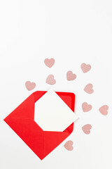 Top view of red envelope, white card on white background. Valentine's day, pink glitter hearts, love. Post flat lay, copy space.