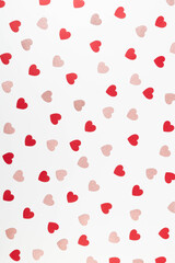 Top view of red and pink glitter hearts on white background. Valentine's day, pink glitter hearts, red hearts, love wallpaper. Flat lay, copy space.