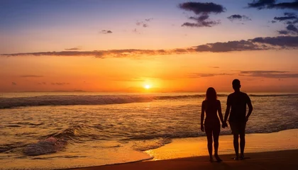 Sunset at the beach with silhouettes of a couple holding hands near the water