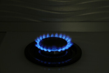 Gas burner of modern stove with burning blue flame at night