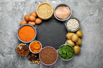 Diet plan for anemia. Different products rich in iron and slate board on grey table, flat lay. Space for text