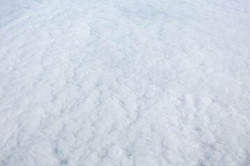 Aerial view over surface of white dense clouds