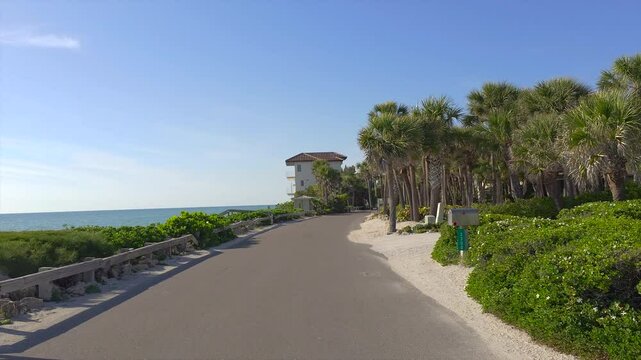 Florida travel concept. Car POV driving on Casey Key scenic road with tropical nature and wealthy coastal houses.