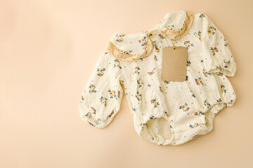 Close-up of a floral baby dress with lace details and an eco-friendly kraft paper tag on a soft...