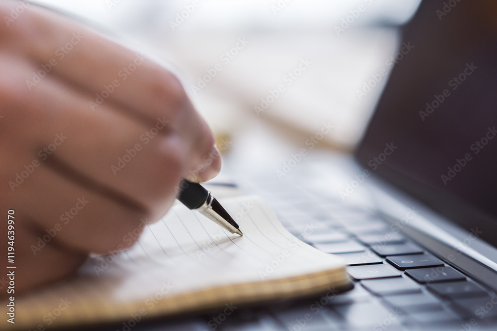 Poster sharp view of a woman's hand transcribing in a notepad on a cutting-edge laptop, with a defocused ba